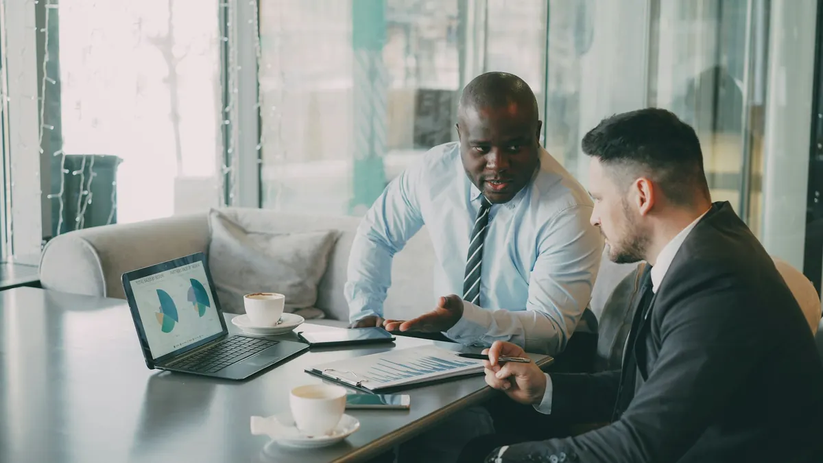 Two colleagues reviewing financial charts on a laptop in a meeting